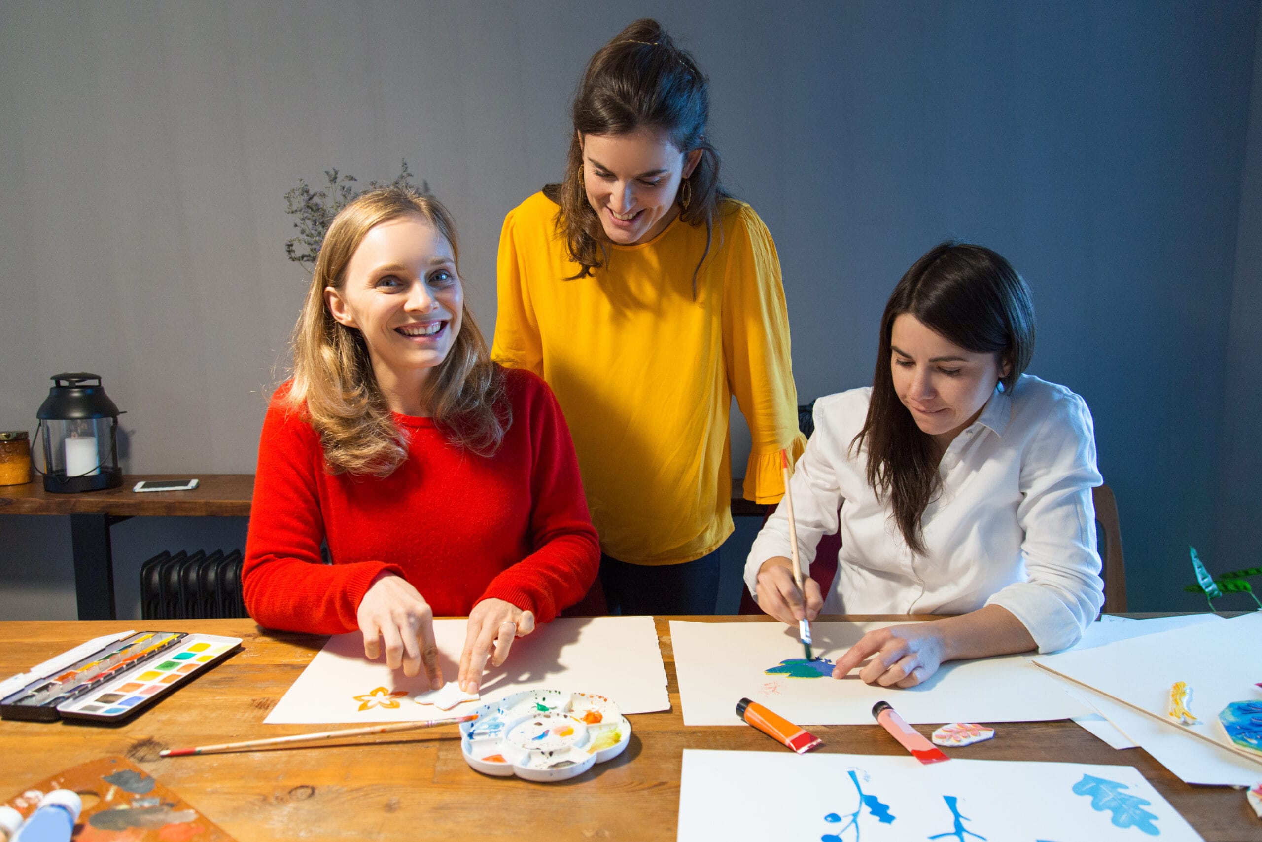 Cheerful art teacher and students enjoying painting class.